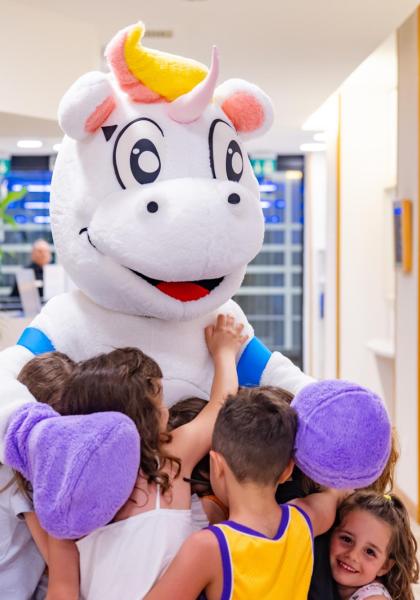Bambini abbracciano un costume da unicorno in un ambiente allegro.