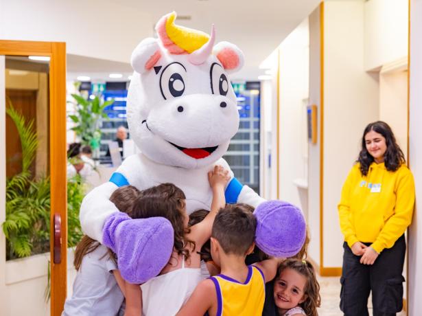 Bambini abbracciano un costume da unicorno in un ambiente allegro.