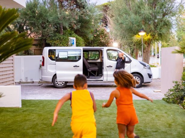 Children run towards a van with a man waving.