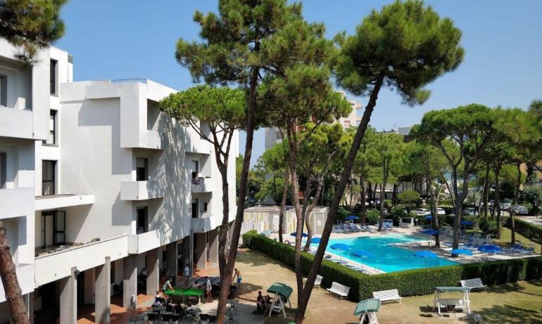 Complesso residenziale con piscina e alberi alti.