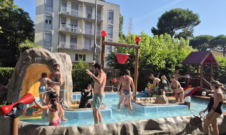 Families play in outdoor pool with water games.