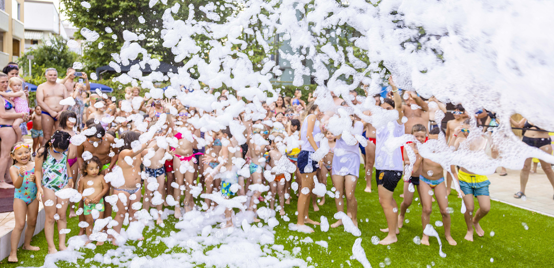 Joyful children play with foam at an outdoor party.