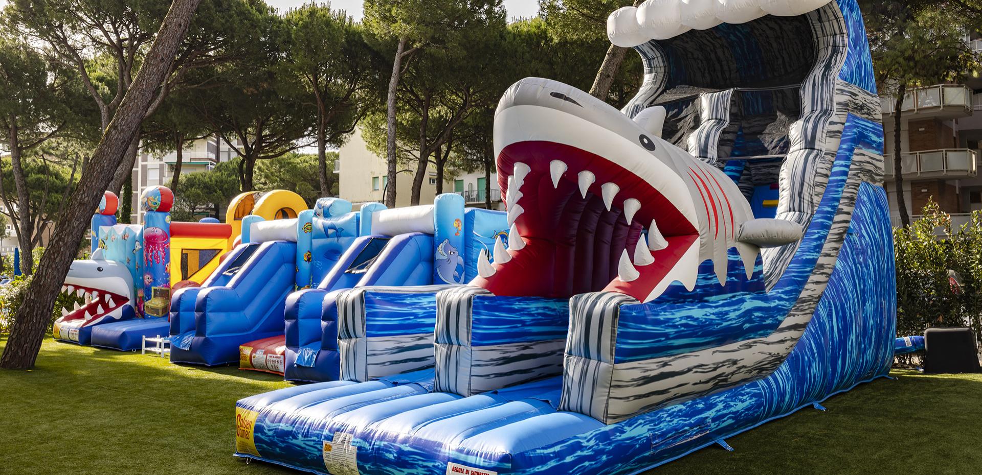 Colorful inflatables with a giant shark in a green park.