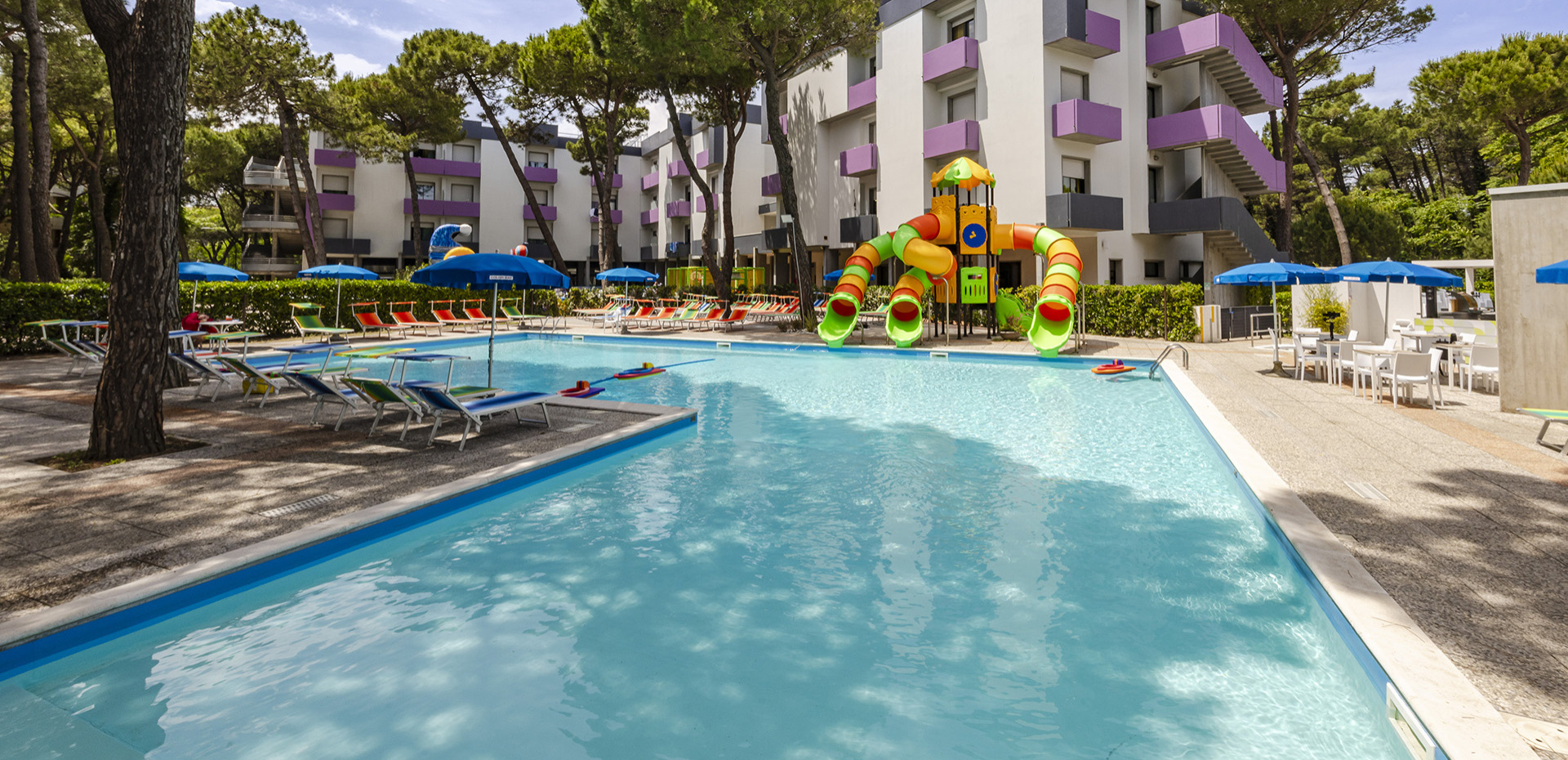 Piscina con giochi acquatici e gonfiabili colorati in un ambiente soleggiato.