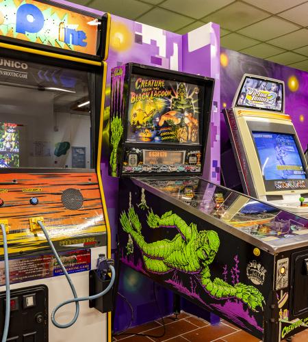 Two people joyfully play an arcade game with colorful guns.