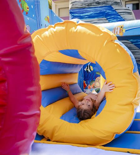 Joyful kids sliding down a colorful inflatable, full of excitement.