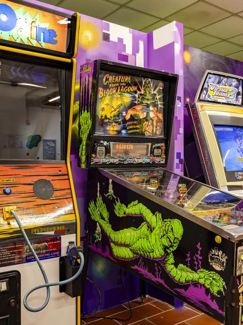 Two people joyfully play an arcade game with colorful guns.