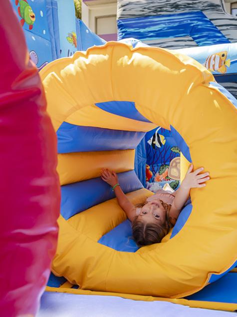 Joyful kids sliding down a colorful inflatable, full of excitement.