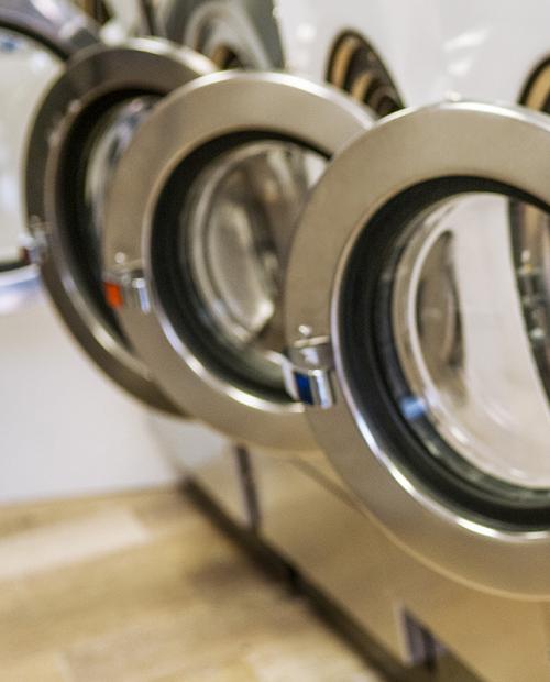 Rangée de machines à laver en acier, évoquant ordre et propreté.