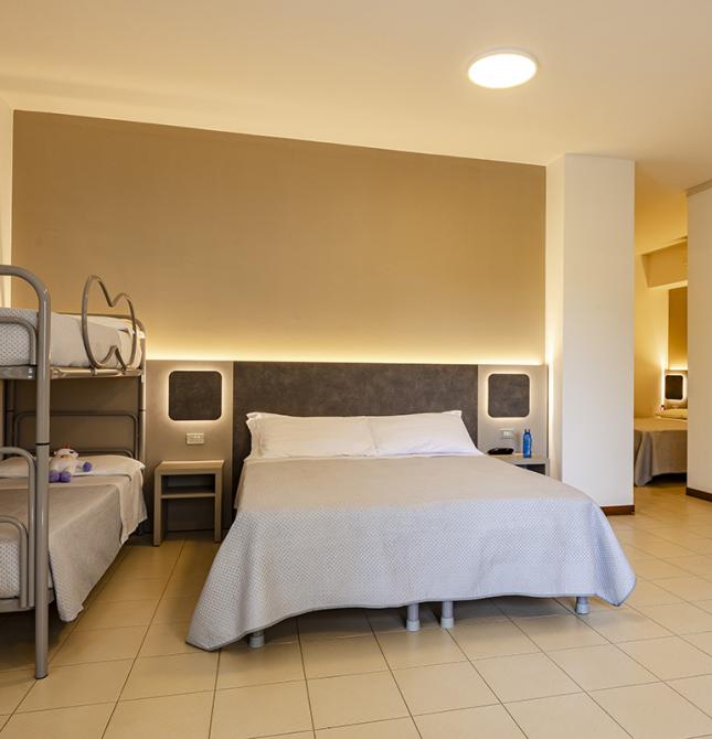 Chambre accueillante avec lit double et lits superposés, ambiance chaleureuse et relaxante.