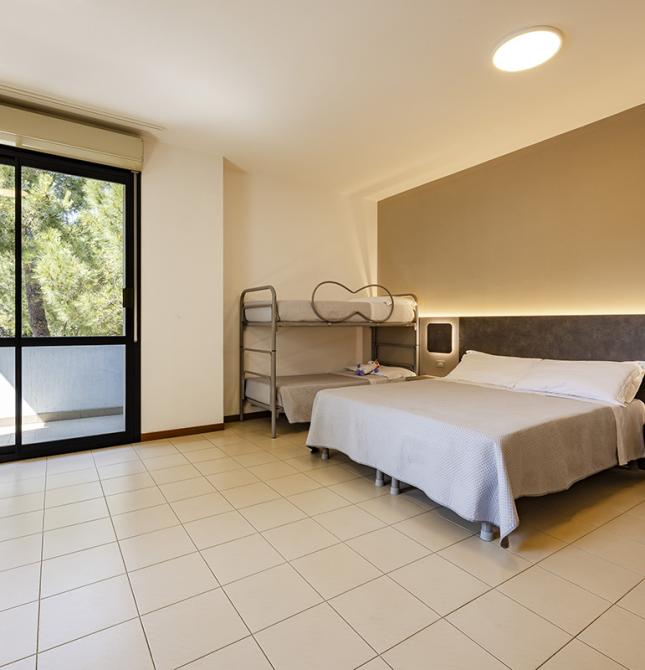 Chambre lumineuse avec lit double, lits superposés et rideaux jaunes.
