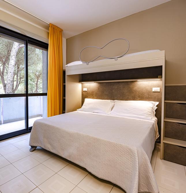 Chambre lumineuse avec lit double et balcon entouré de nature.